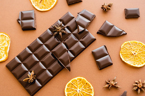 Top view of chocolate, dry orange slices and anise on brown background