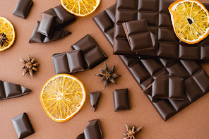 Top view of dry orange slice, anise and chocolate on brown background