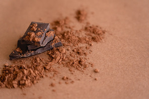 Close up view of dark chocolate and cocoa powder on brown background with copy space