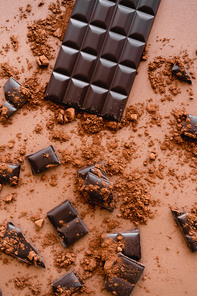 Top view of natural dark chocolate and cocoa on brown background