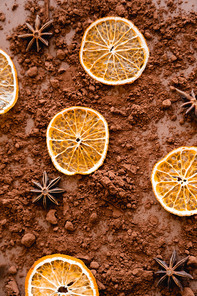 Top view of dry orange slices and anise on cocoa on brown background