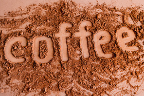 Top view of coffee lettering in cocoa on brown background