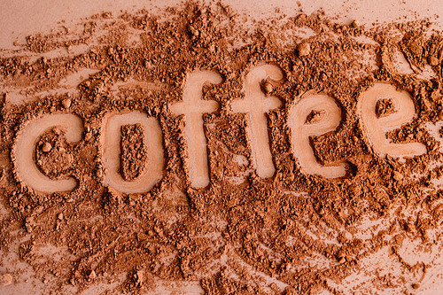 Top view of coffee lettering in cocoa on brown background
