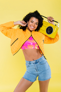 cheerful african american young woman holding boombox isolated on yellow