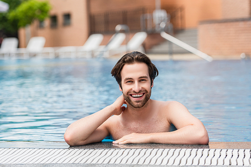 Young man smiling at camera in water of swimming pool