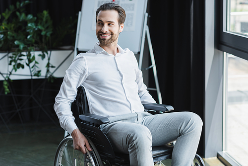 cheerful handicapped businessman looking away and smiling in office