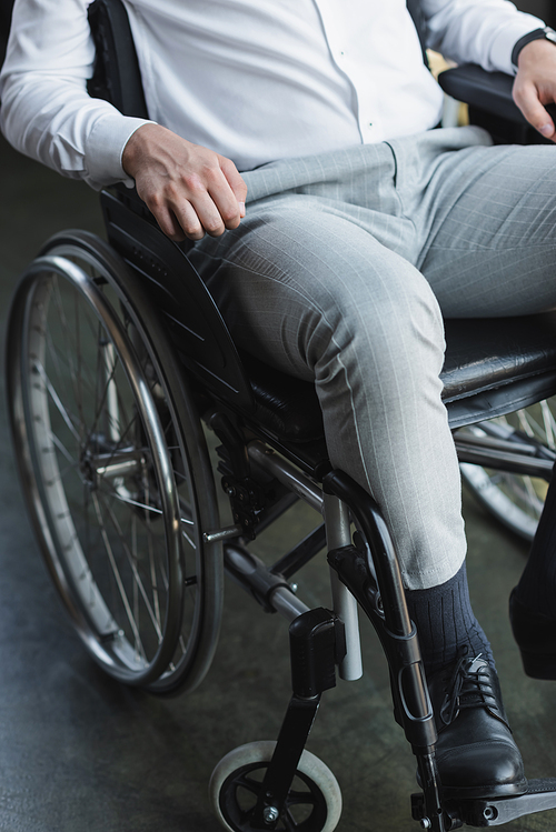 partial view of disabled businessman sitting in wheelchair in office