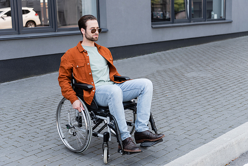 young handicapped man in wheelchair on pavement with border in city