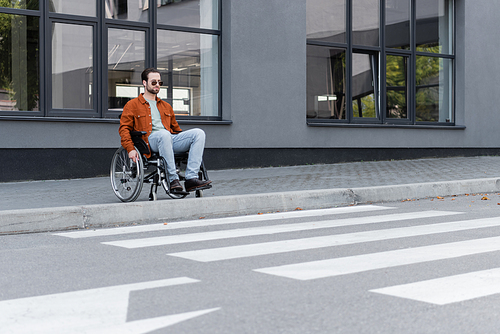 young handicapped man sitting in wheelchair near border and crosswalk