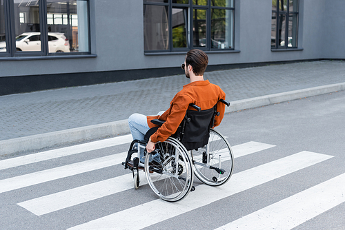 young disabled man crossing road in wheelchair