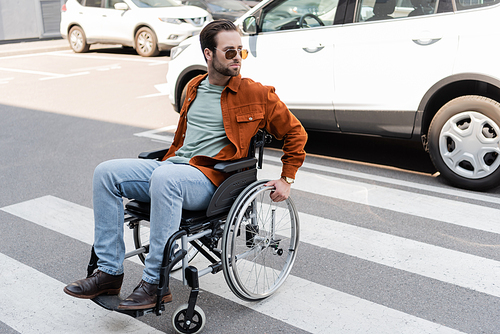 handicapped man in sunglasses crossing road on wheelchair