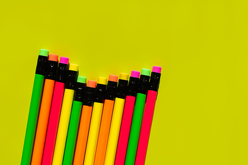 top view of pencils with erasers on green background