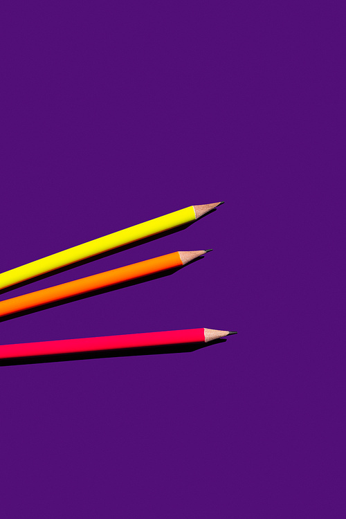 top view of colorful pencils on purple background