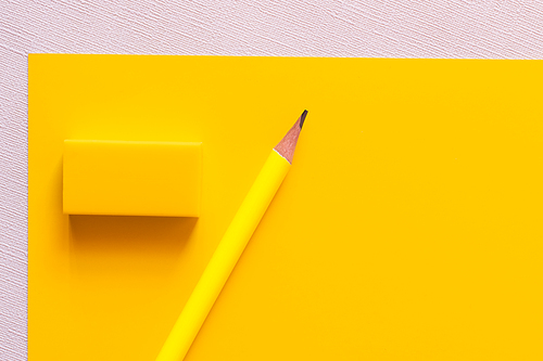 top view of pencil near eraser on yellow and white