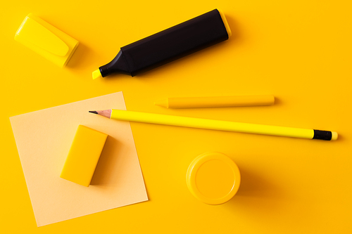 top view of stationery and marker pen near paper note on yellow