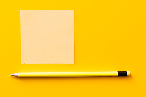 top view of sharp pencil near blank paper note on yellow