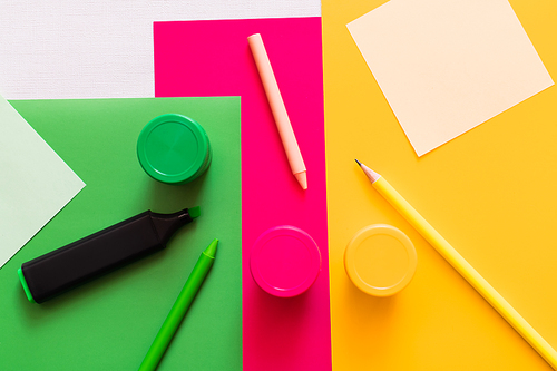 top view of stationery near jars with paint on colorful background