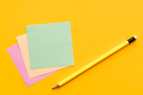 top view of pencil near multicolored paper notes on yellow background