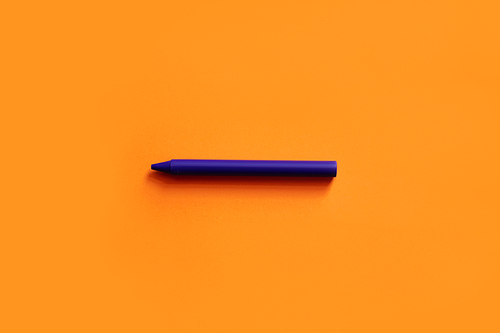 top view of purple crayon on orange background