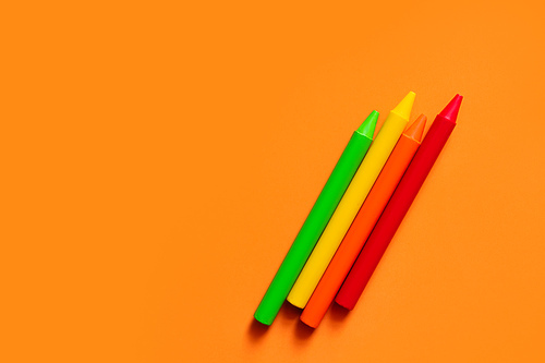 top view of colorful crayons on orange background
