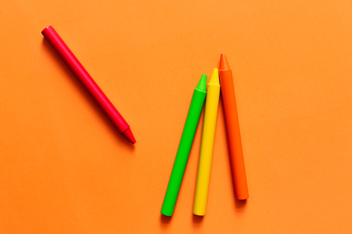 top view of set with colorful crayons on orange background