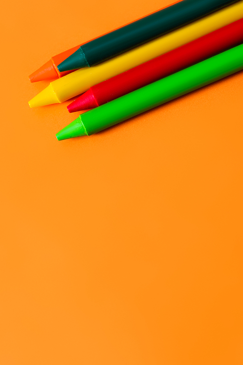 top view of set with colorful wax crayons on orange background