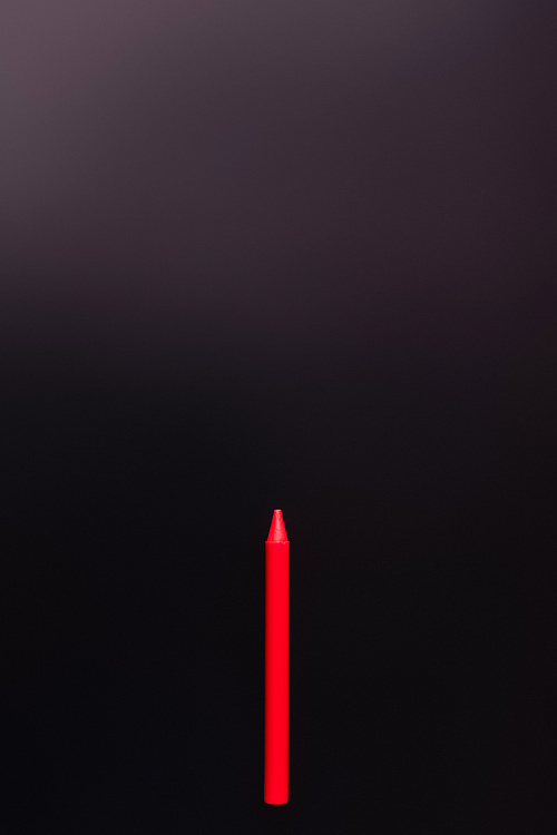 top view of red crayon on black background