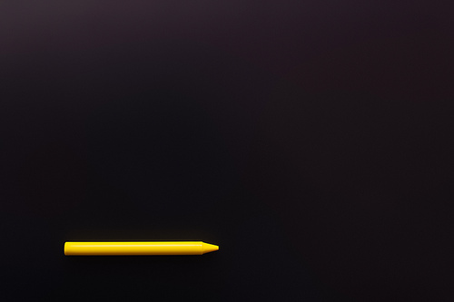 top view of yellow crayon on black background