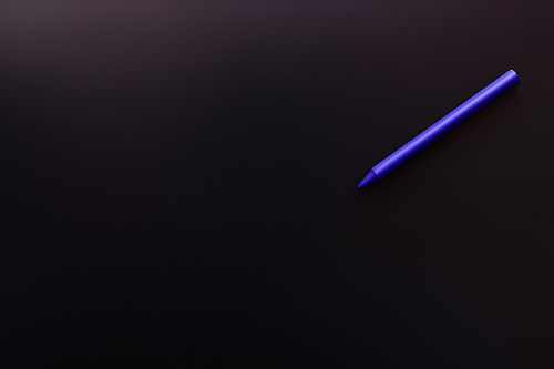 top view of blue crayon on black background
