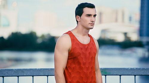 young sportsman in red tank top standing on bridge