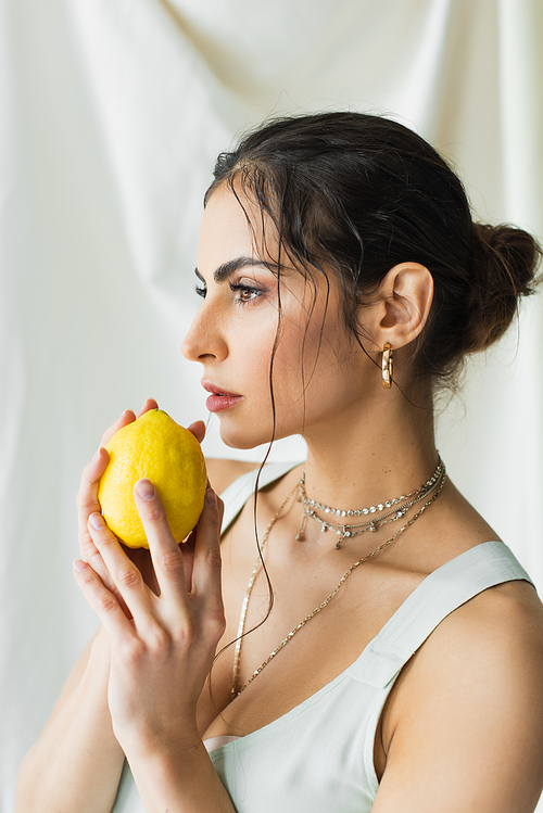 pretty woman in dress holding fresh lemon on white