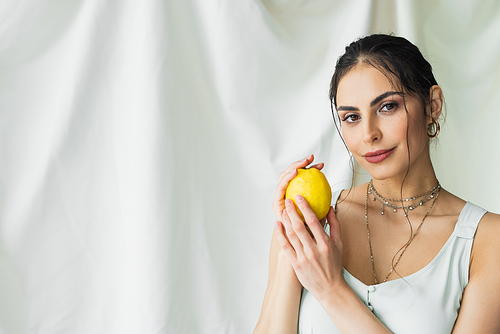 smiling woman in dress holding fresh lemon on white
