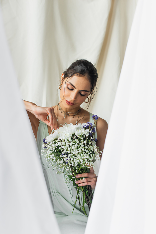 brunette woman looking at bouquet of flowers on white
