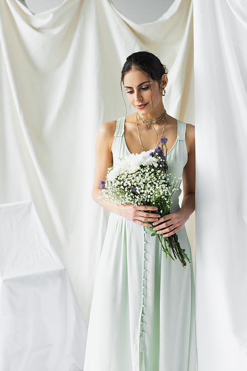pretty woman in dress holding bouquet of flowers on white