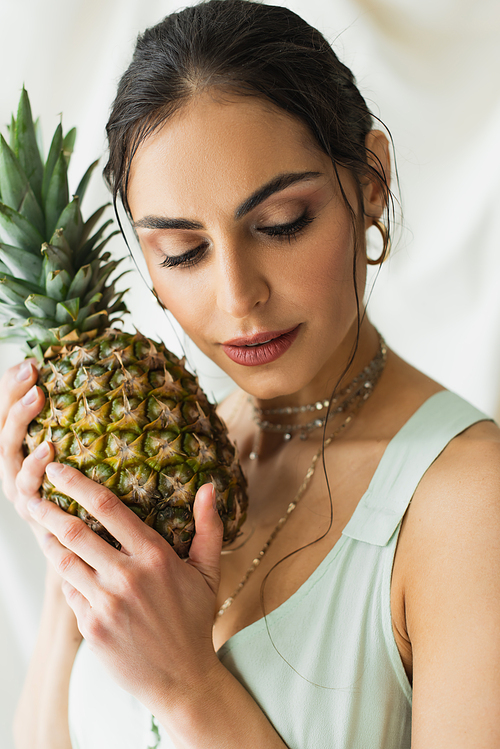 brunette model posing near ripe pineapple on white