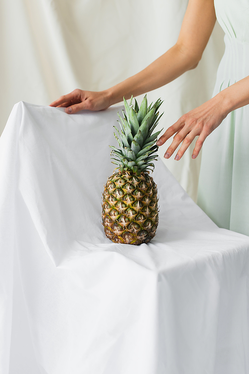 cropped view of model posing near ripe pineapple on white