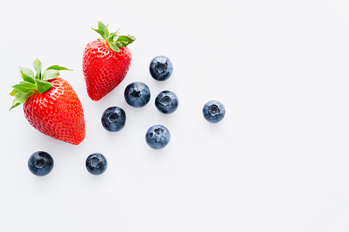 Top view of fresh blueberries and strawberries on white background