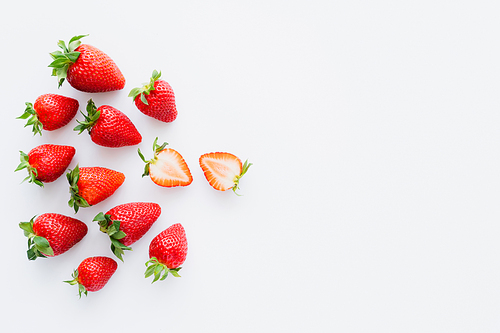 Top view of cut and whole strawberries on white background
