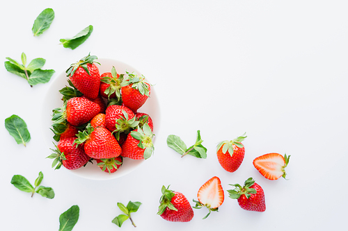 Top view of fresh strawberries and blurred mint leaves on white background