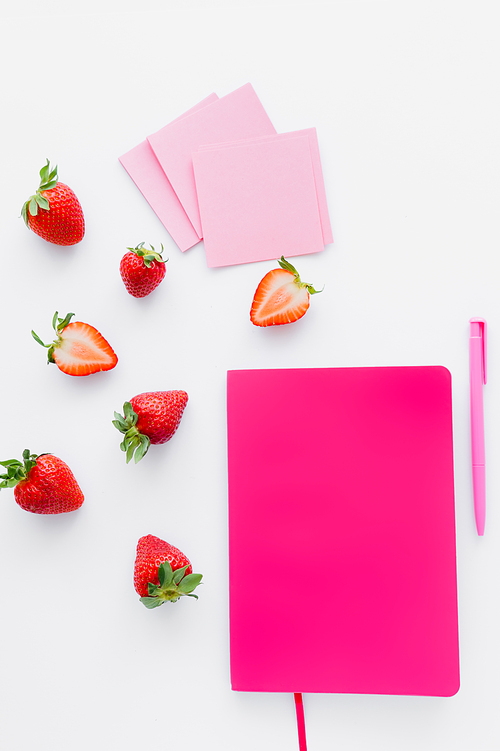 Top view of notebook near sticky notes and strawberries on white background