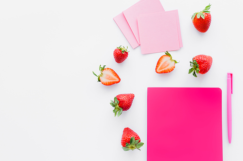 Top view of ripe strawberries near notebook and sticky notes on white background