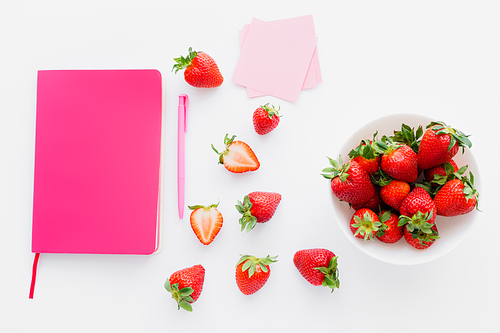 Top view of pink notebook and fresh strawberries on white background