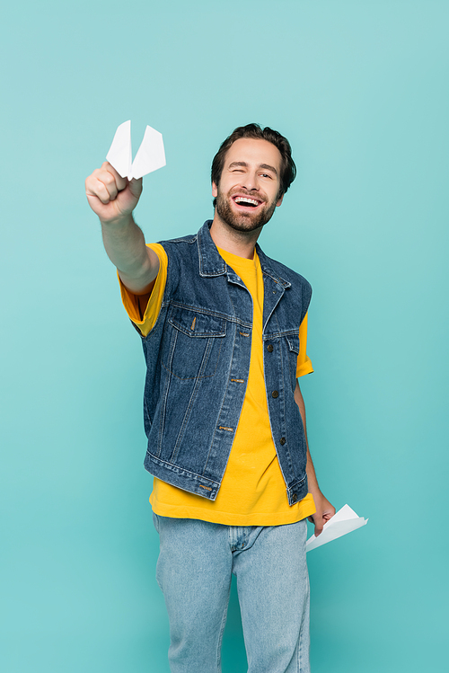 Smiling man holding paper planes isolated on blue