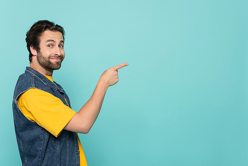 Brunette man smiling and pointing with finger isolated on blue