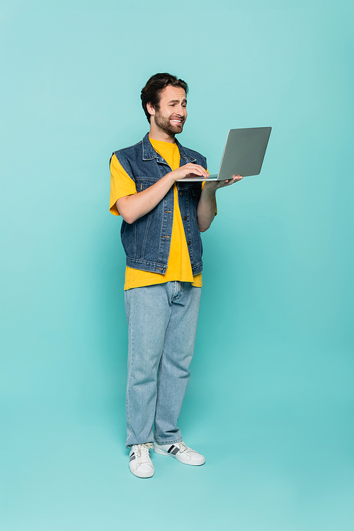 Smiling teleworker using laptop on blue background