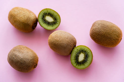 top view of sweet whole and cut kiwi on pink
