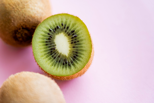 top view of cut kiwi near whole fruit on pink