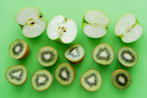flat lay of apples and kiwi fruits halves on green