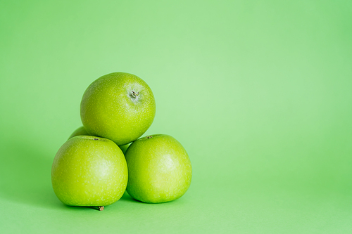 whole and fresh apples on green background