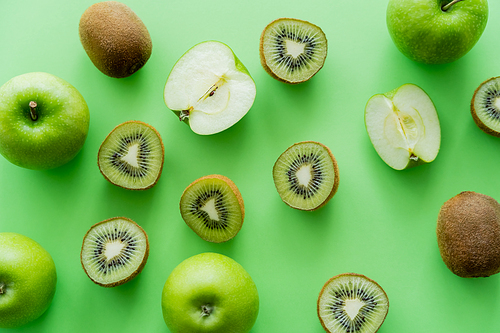 top view of tasty kiwi and apples on green